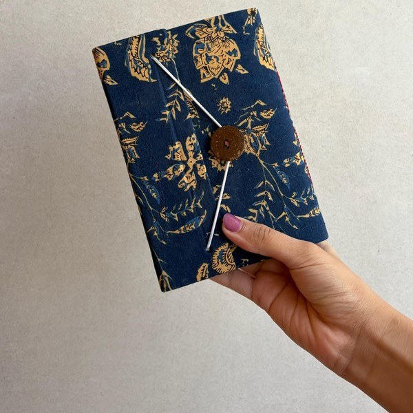A floral hand block printed notebook in navy and gold with a button closure.